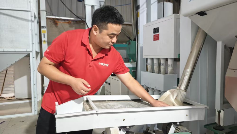 周地帅在新安装的大米加工生产线前查看新加工的大米。新华社记者 陈诺 摄