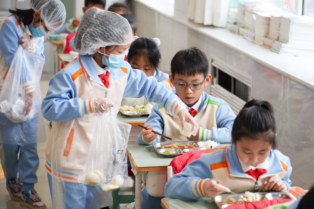 2026年3月2日,北京首都师范大学附属小学三年级3班分餐员在教室分馒头。新华社记者 谢晗 摄